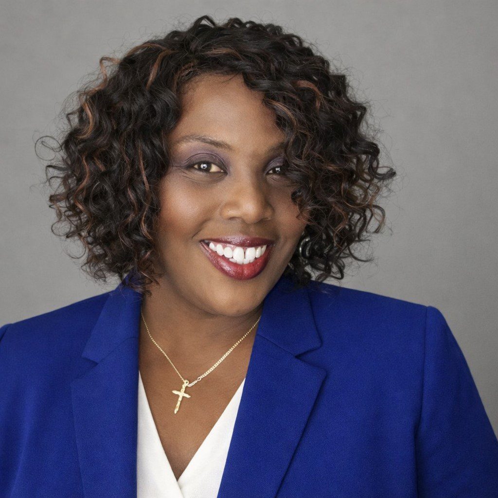 Smiling woman wearing blue blazer and cross necklace